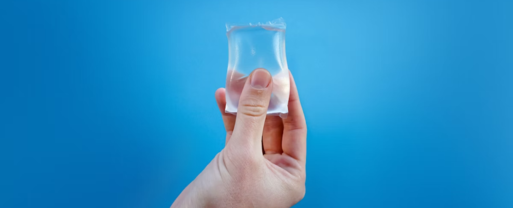 Person holding piece of plastic on blue background