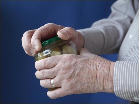 A pair of hands struggling to open a jar of pickles